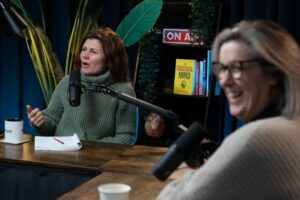 An image of two women having a discussion on the set of a podcast