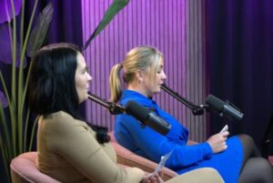 A image of two women on the set of a podcast speaking into microhpones